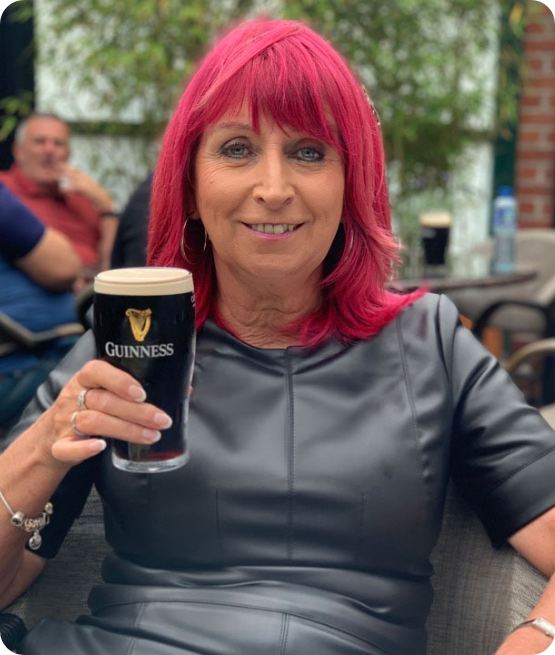 Joan smiling while holding a pint of Guinness, bringing warmth and personality to her role with Midlands Irish Construction Network.
